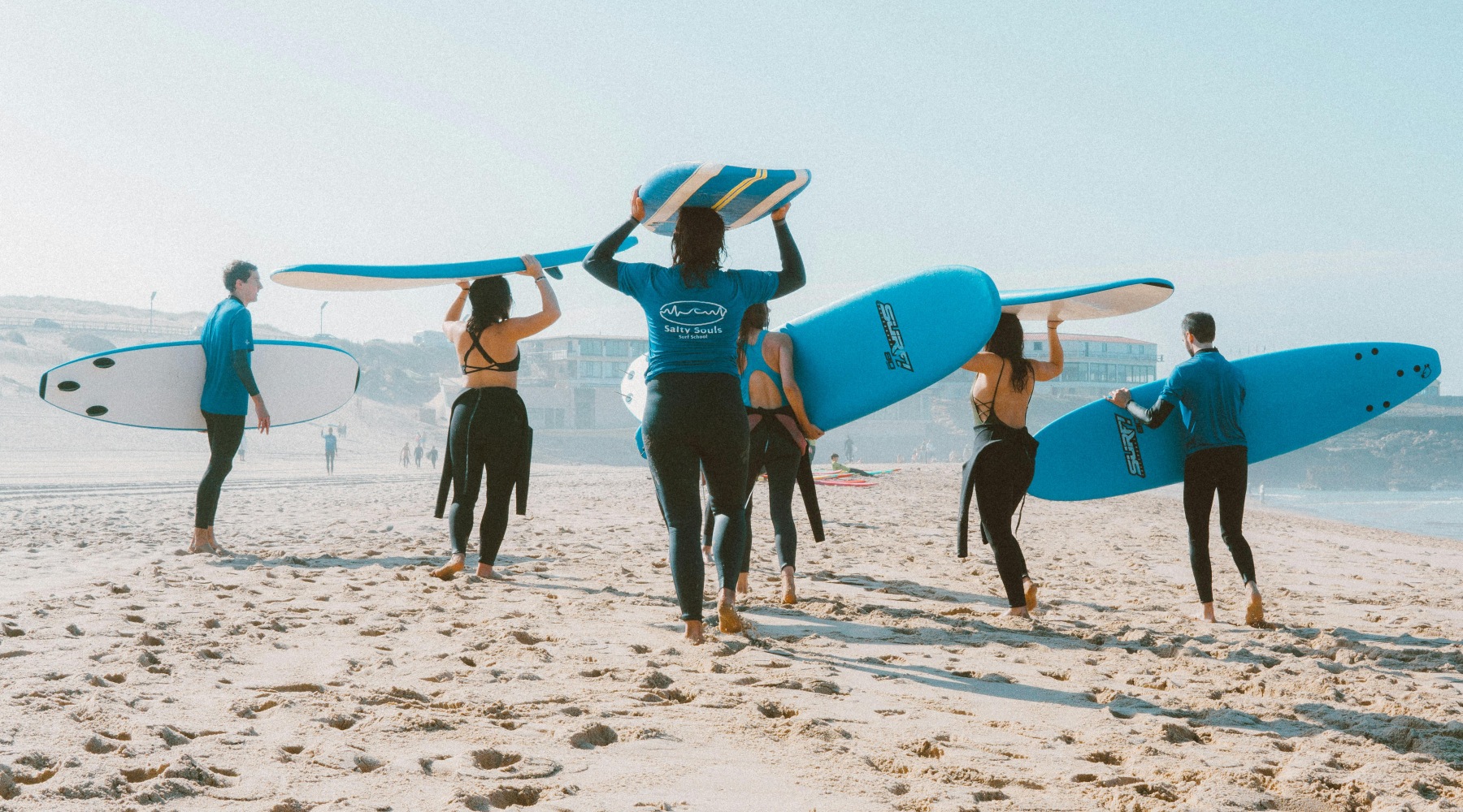 People Running on Beach with Surfboards